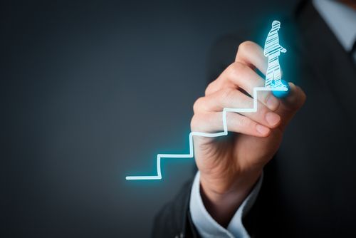 Man's hand drawing stairs with person climbing